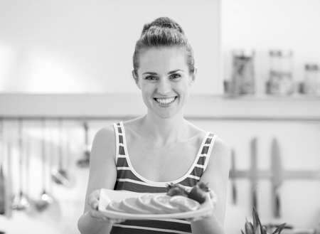 Happy young woman holding plate with strawberry and orangeの写真素材