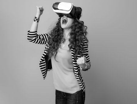 cheerful stylish woman in striped jacket and virtual reality gear isolated on rejoicing