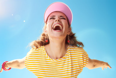 happy healthy woman in yellow shirt against blue sky rejoicing