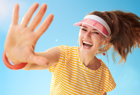 happy healthy woman in yellow shirt against blue sky high fiveの写真素材