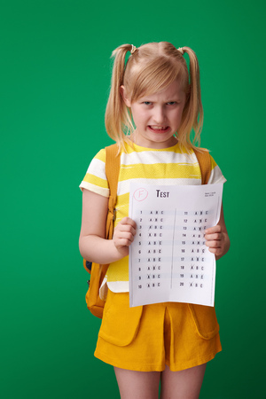 angry pupil with backpack received a bad grade against green backgroundの写真素材