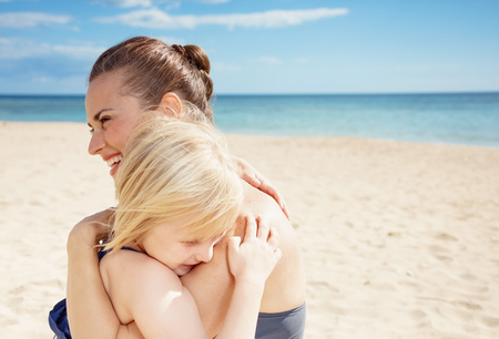 Smiling young mother and daughter in beachwear on the seacoast huggingの写真素材
