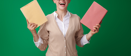 smiling young student woman with books jumping on green backgroundの写真素材