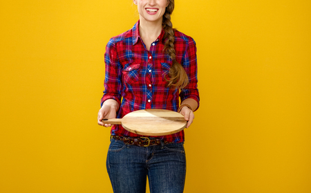 Healthy food to your table. Closeup on smiling modern woman grower in checkered shirt isolated on yellow background showing an empty treyの写真素材