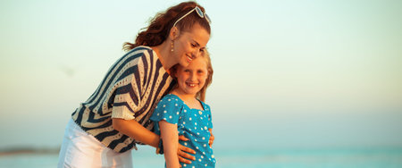 happy modern mother and child on the beach at sunset hugging