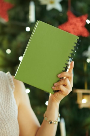 happy modern woman near Christmas tree showing notebookの写真素材