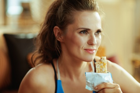 Portrait of healthy woman in sport clothes with fitness bar in the modern living room.の写真素材