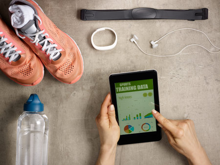 Closeup on sneakers, heart rate monitor, bottle of water, white fitness tracker, headphones laying...