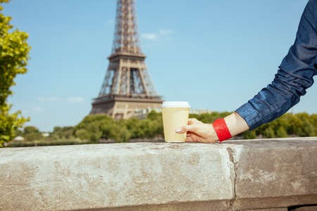 Closeup on smiling coffee cup in hand of tourist woman not far from Eiffel tower in Paris, France.の写真素材