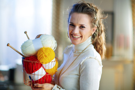 Portrait of smiling stylish 40 years old housewife in white sweater and skirt with basket with...