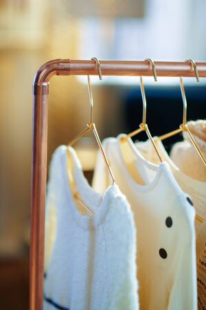 Closeup on modern copper clothes rack with clothes on hangers.の写真素材