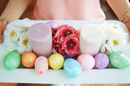 Closeup on housewife in the house in sunny spring day holding easter decorated plate.の写真素材