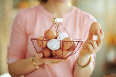 Closeup on female holding basket with eggs and showing egg in the living room in sunny spring day.