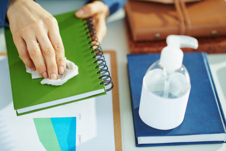Closeup on woman sanitising stuff with a disinfectant in temporary home office during the coronavirus epidemic at home in sunny day.の写真素材