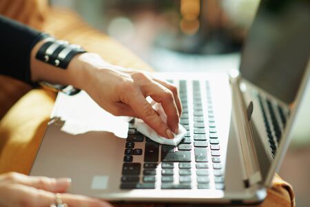 Closeup on housewife cleaning laptop keyboard with cleaning cloth in the house in sunny day.の写真素材