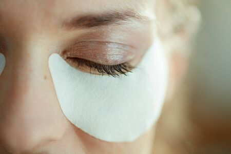Closeup on woman in the house in sunny day using white cotton eye patches.の写真素材