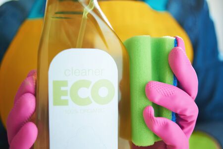Closeup on woman with spray bottle of eco friendly cleaning supplies and green sponge in the house in sunny day.の写真素材
