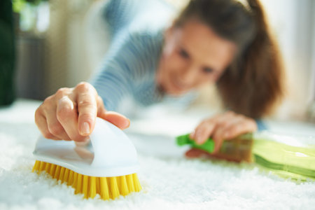 Closeup on woman in striped t-shirt and white pants with spray bottle of eco friendly cleaning...