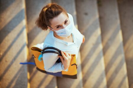 Life during covid-19 pandemic. Upper view of stylish female in blue blouse with medical mask, handbag and sanitizer outdoors in the city.の写真素材