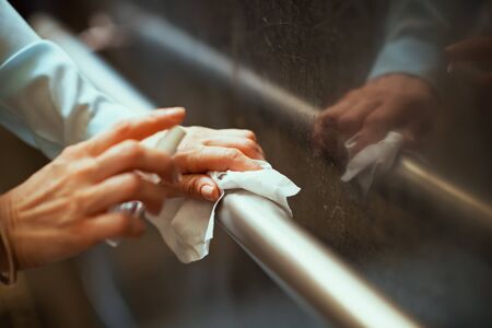 Life during covid-19 pandemic. Closeup on woman disinfecting railing with sanitiser.の写真素材