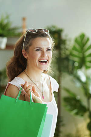 Portrait of happy trendy 40 years old woman shopper in pink blouse with credit card and paper shopping bags.の写真素材