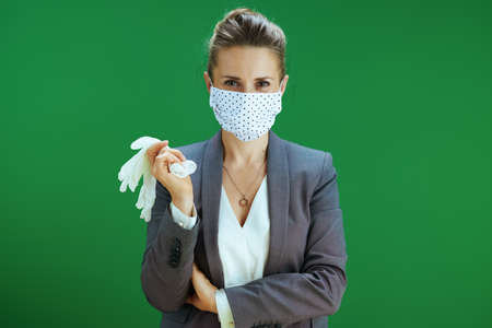 Portrait of modern woman pedagogue in white blouse with medical mask against chalkboard green background.の写真素材