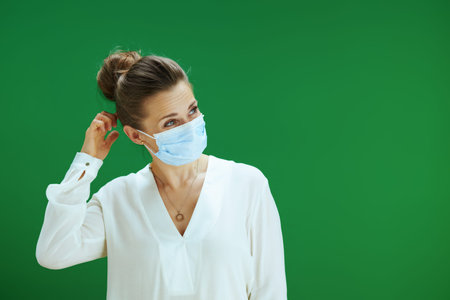40 years old woman teacher with medical mask isolated on chalkboard green background.