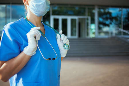 coronavirus pandemic. Closeup on medical doctor woman in scrubs with stethoscope and medical mask outdoors near hospital.の写真素材