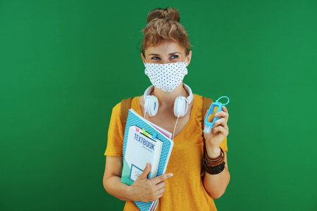Life during coronavirus pandemic. Portrait of modern student woman in yellow shirt with medical...