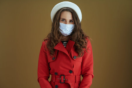 Hello autumn. Closeup on middle aged woman in red coat with yellow autumn maple leaf showing smartphone blank screen against bronze background.の写真素材