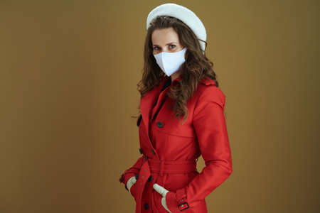 Hello autumn. Closeup on middle aged woman in red coat with yellow autumn maple leaf showing smartphone blank screen against bronze background.の写真素材