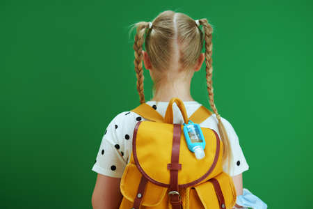 Life during coronavirus pandemic. modern girl in white blouse with yellow backpack and pink mask isolated on chalkboard green background.の写真素材