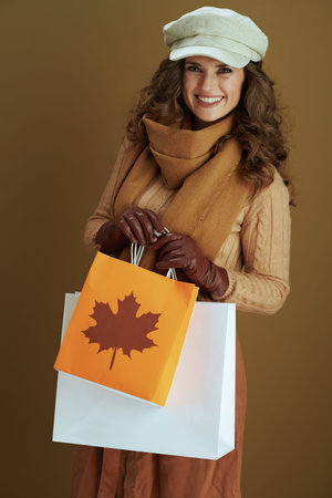 Hello october. smiling stylish 40 years old woman in scarf with leather gloves and paper shopping...