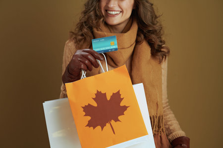 Hello october. smiling stylish 40 years old woman in scarf with leather gloves and paper shopping...