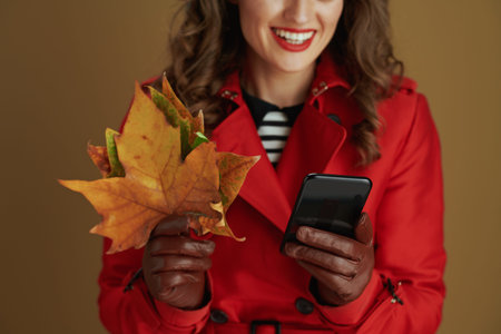 Hello autumn. happy middle aged housewife in red coat and black beret with leather gloves and yellow...