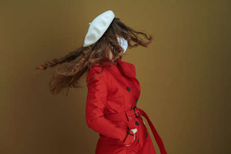 Hello autumn. Portrait of happy modern middle aged woman in red coat showing smartphone blank screen against beige background.の写真素材