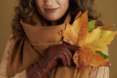 Hello autumn. pensive elegant female in scarf with leather gloves and paper shopping bag isolated on beige.の写真素材
