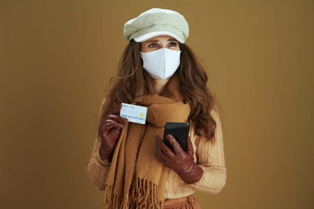 Life during covid-19 pandemic. stressed modern female in scarf with white medical mask on beige...