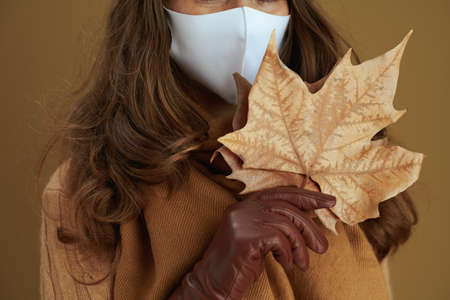 Life during coronavirus pandemic. elegant housewife in sweater with smartphone, white medical mask and credit card buying on internet isolated on beige background.の写真素材