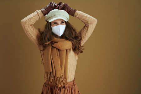 Life during coronavirus pandemic. elegant housewife in sweater with smartphone, white medical mask and credit card buying on internet isolated on beige background.の写真素材