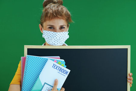 Life during covid-19 pandemic. Portrait of happy modern student in yellow shirt with medical mask...
