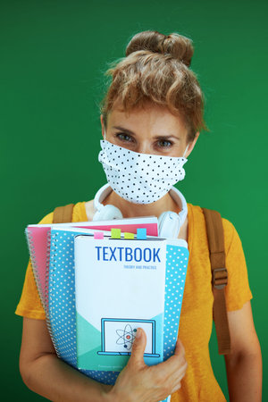 Life during coronavirus pandemic. Closeup on student woman with backpack putting additional medical...