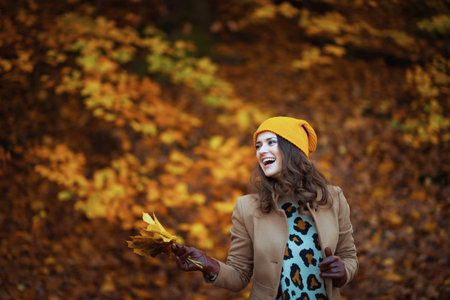 Hello autumn. Closeup on woman standing in boots on the green grass with autumn leaves outdoors in...