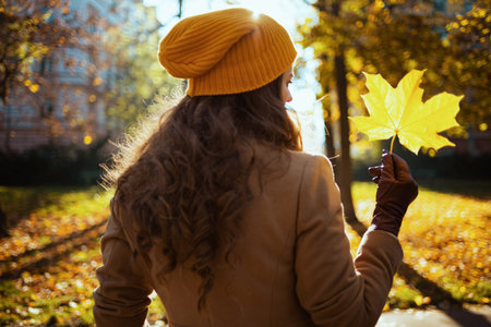 Hello autumn. Closeup on woman standing in boots on the green grass with autumn leaves outdoors in the city park in autumn.の写真素材