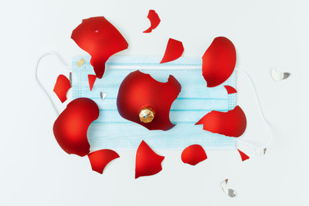 flat lay with medical mask and broken christmas ball on green background.の写真素材