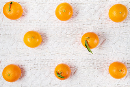 winter flat lay with medical mask and mandarins on white knitted background.の写真素材