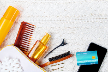 winter flat lay with credit card, cosmetics, snowflake and smartphone on white knitted background.の写真素材