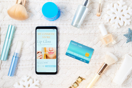 winter flat lay with credit card, cosmetics, snowflake and smartphone on white knitted background.の写真素材