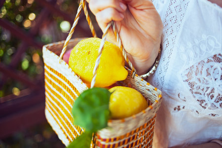 Closeup on woman in white shirt with plate of local farm lemons in the patio.