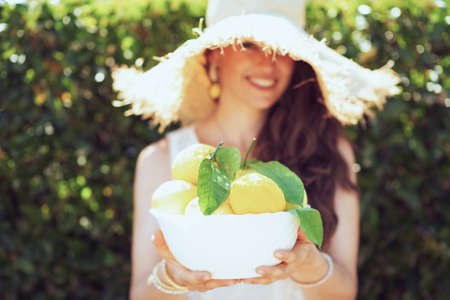 Closeup on woman in white shirt with plate of local farm lemons in the patio.の写真素材